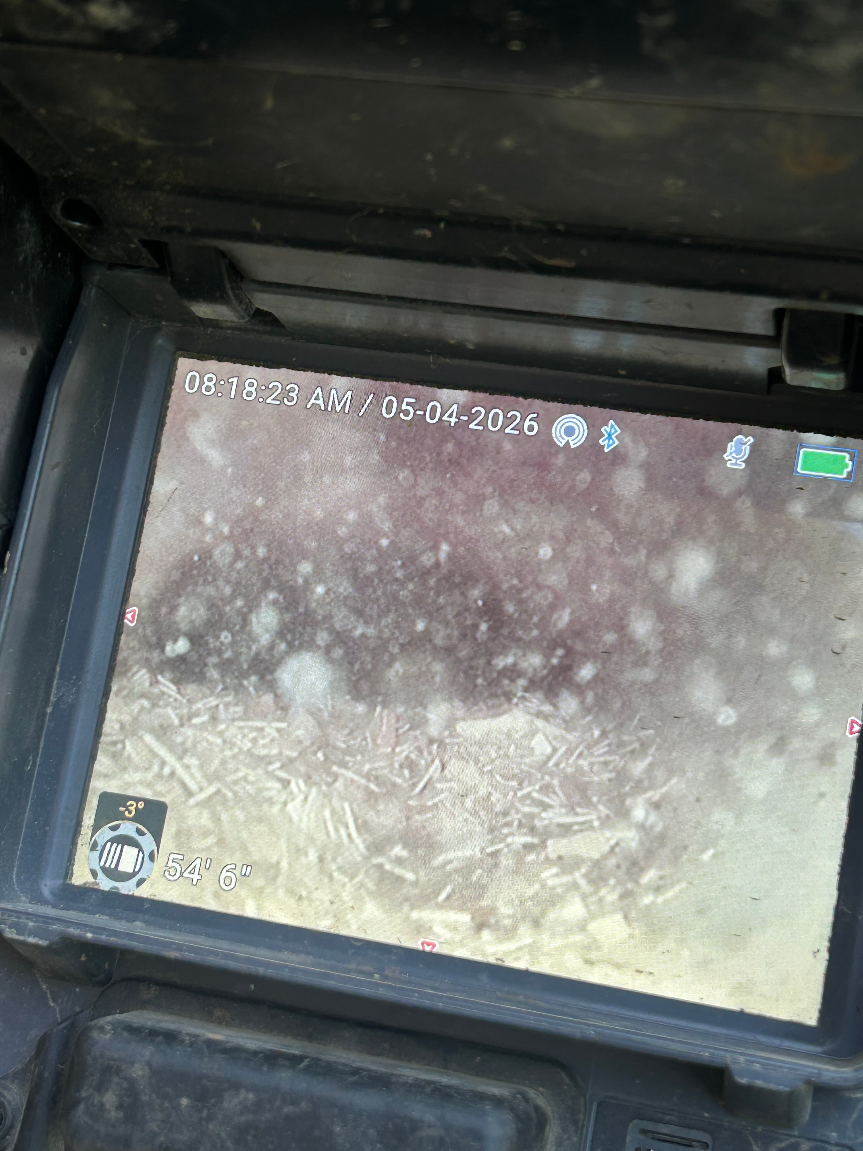 Rugged monitor displaying a grainy pipe inspection with a depth of 54 feet 6 inches.